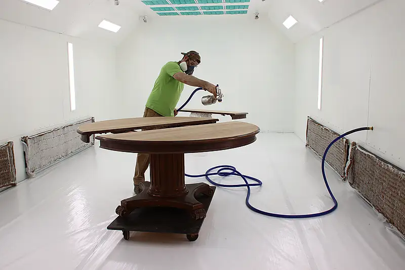 Antique Furniture Refinishing at Harp Gallery Harp Gallery craftsman refinishing an antique dining table in the furniture restoration spray booth