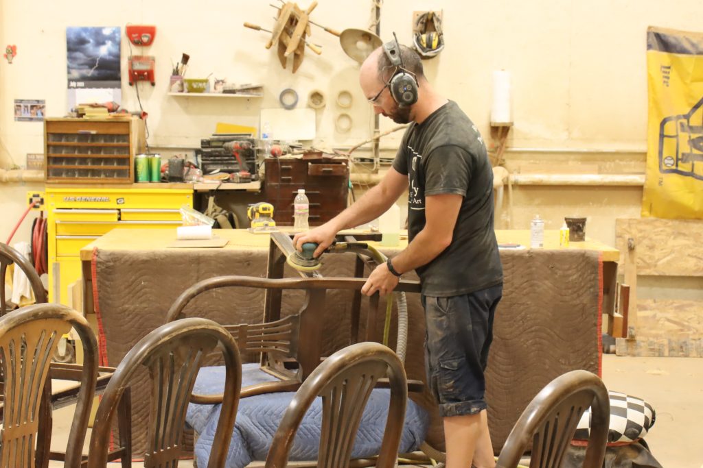 Harp Gallery craftsman sanding a wood chair during antique furniture restoration